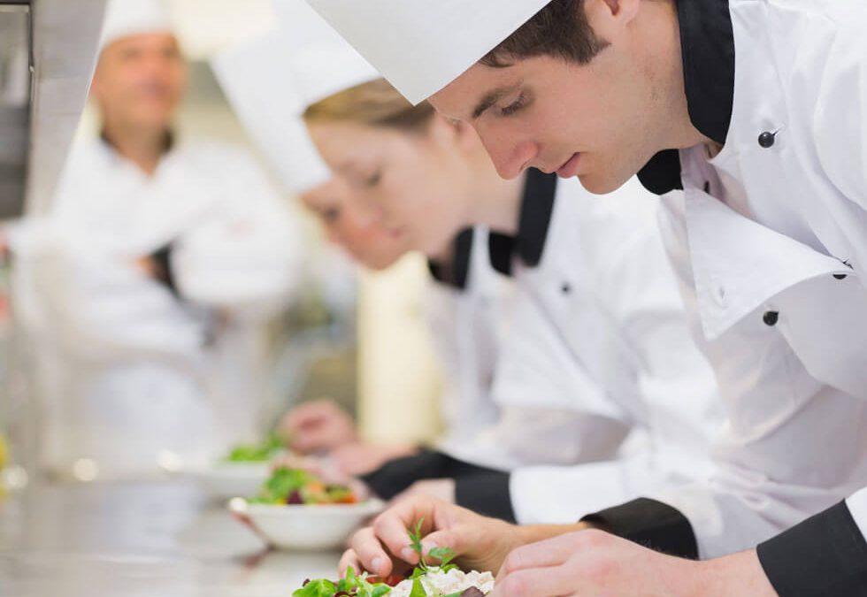 Kochschüler bereiten unter Aufsicht Salat zu