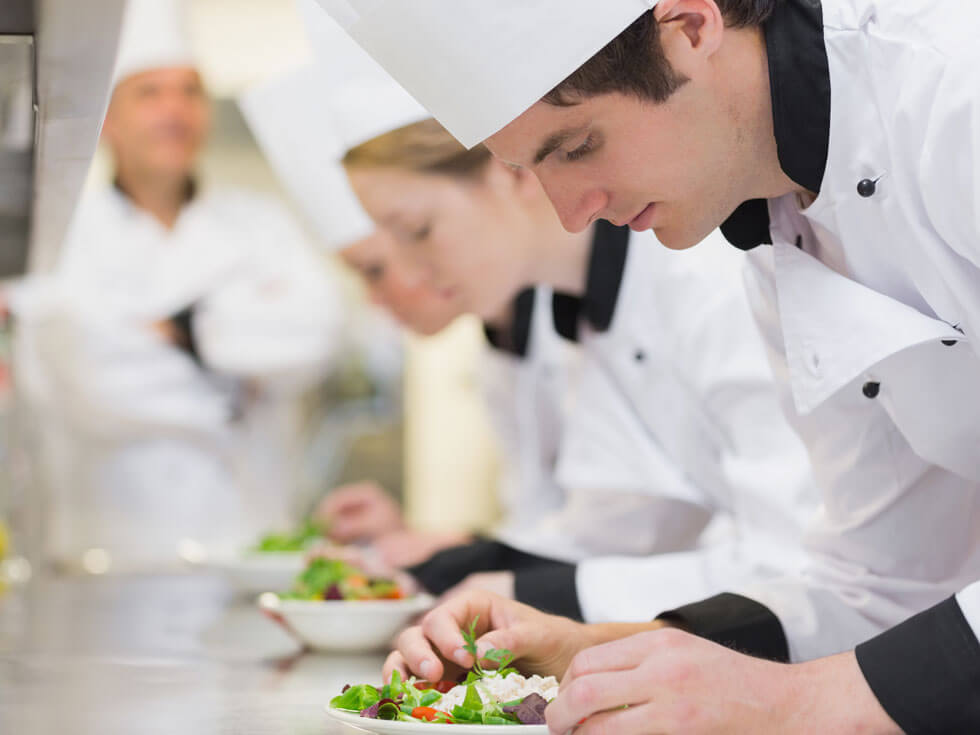 Kochschüler bereiten unter Aufsicht Salat zu