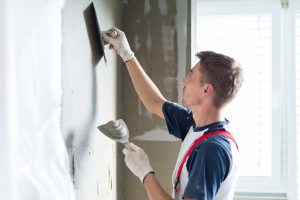 Handwerker streicht Wand mit Beschichtungsmaterial ein