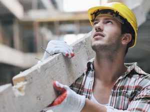 Bauarbeiter auf Baustelle trägt Holzstück