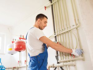 Klempner arbeitet mit Wasserleitungen im Heizraum