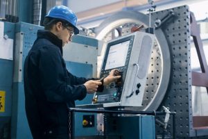Fabrikarbeiter programmiert eine CNC-Fräsmaschine mit einem Tablet-Computer