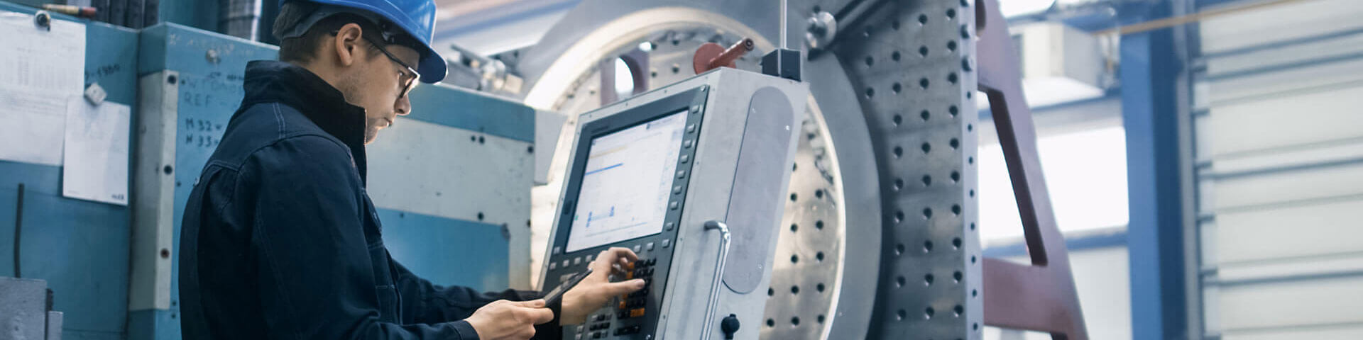 Fabrikarbeiter programmiert eine CNC Fräsmaschine mit einem Tablet-Computer