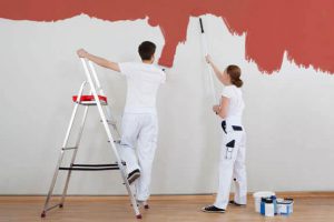Azubis streichen Wand mit roter Farbe an